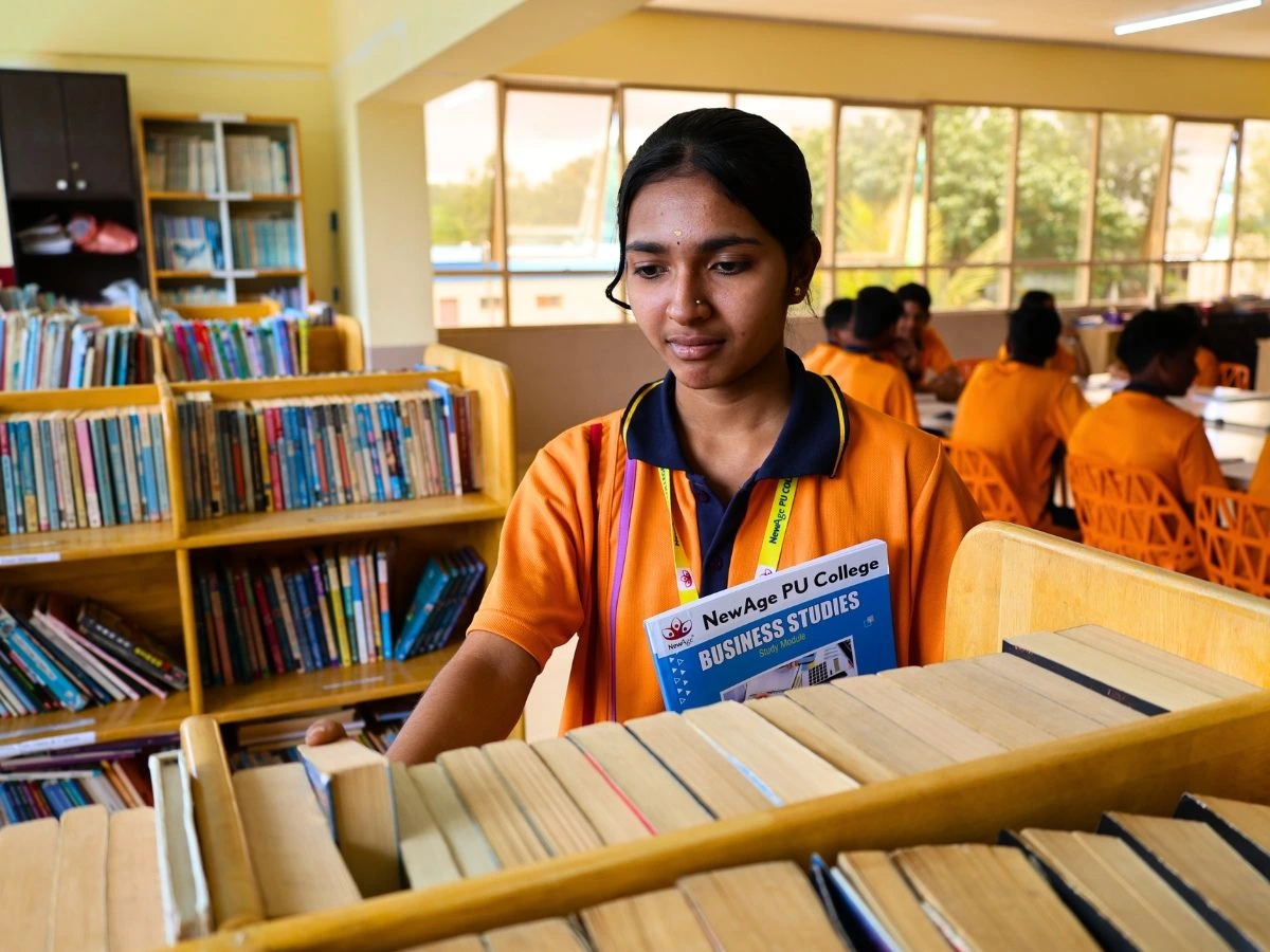Students studying academic books in the college library at NewAge PU College
